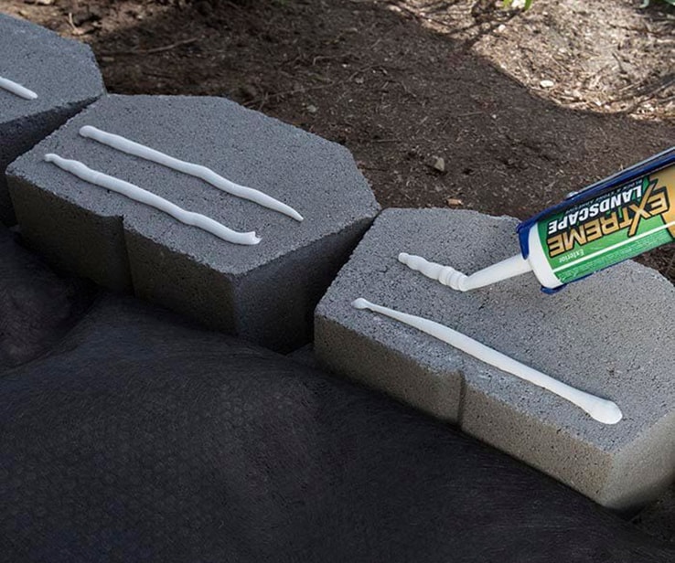 Person applying adhesive onto concrete blocks