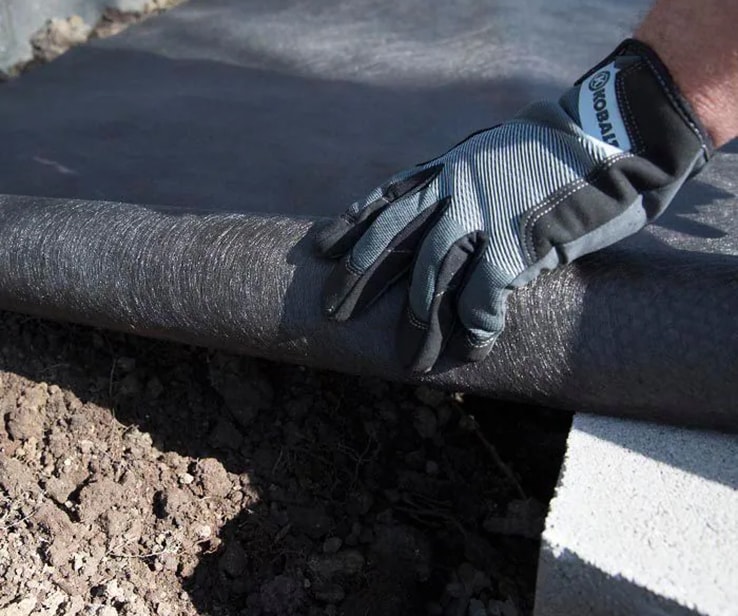 Person adding landscaping fabric to a trench