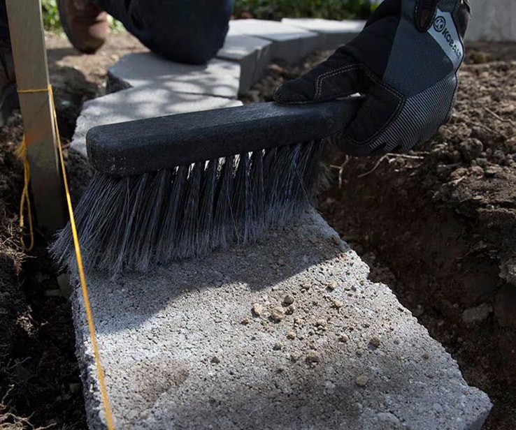 Person cleaning a cement block with a brush