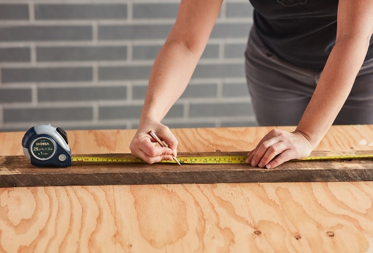 Personne mesurant une planche de bois