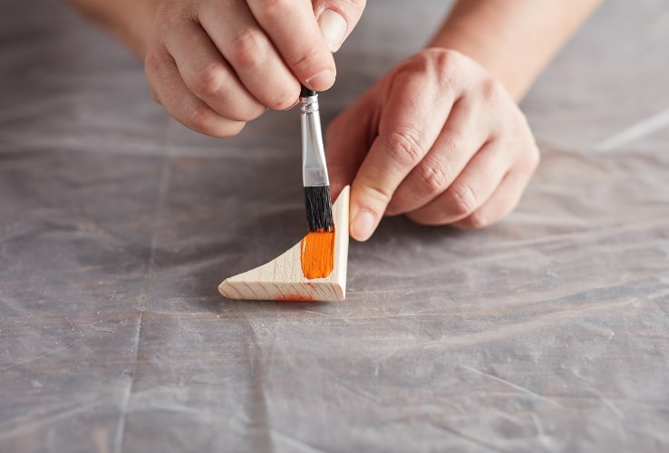 Person painting a scrap of wood