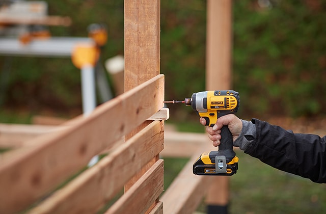 Personne installant des lattes de bois pour créer un panneau d’inimité