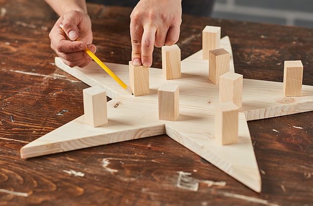 Person marking a piece of wood with a pencil