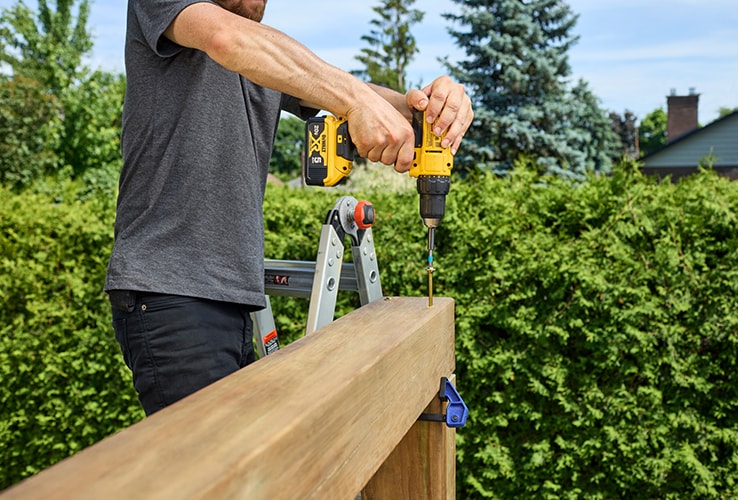 Person assembling the roof of a wood pergola