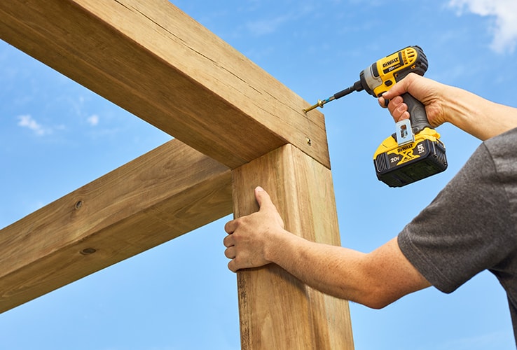 Person assembling the roof of a wood pergola