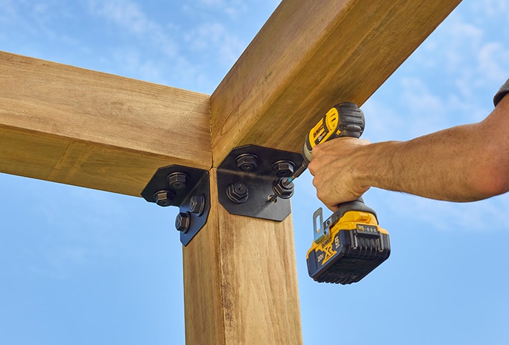 Person adding corner brackets to a pergola