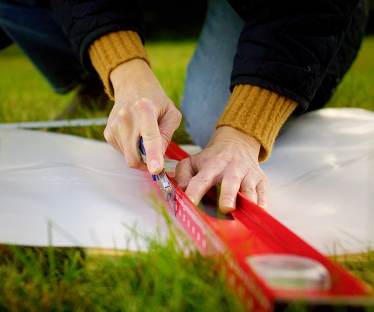 Woman cutting a white plastic sheet