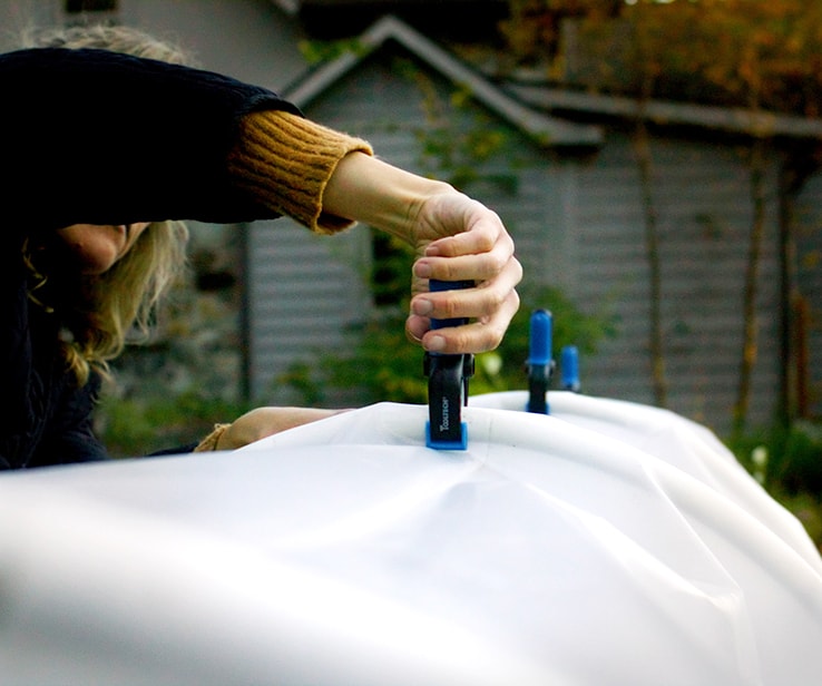 Woman securing a plastic sheet with clamps