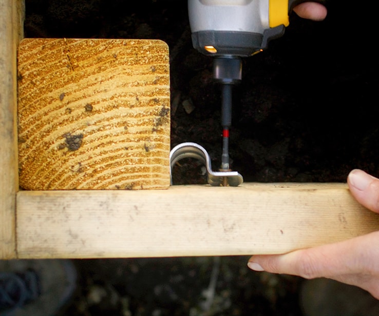 Woman securing metal straps onto a wooden plank