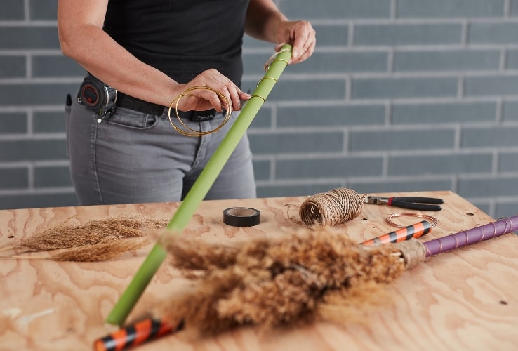 Person decorating wooden witches’ brooms