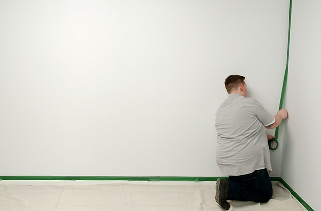 Man applying masking tape around a wall