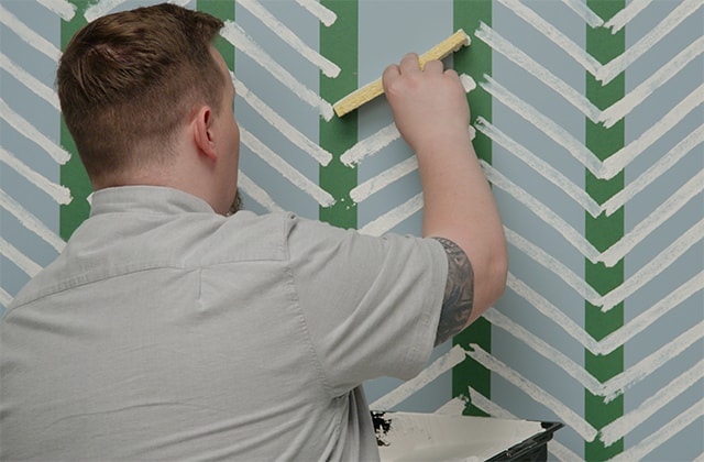 Homme créant un motif de papier peint sur un mur