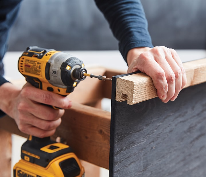 Woman securing a u-shaped moulding using screws