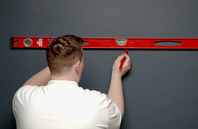 Man tracing a horizontal line on a wall