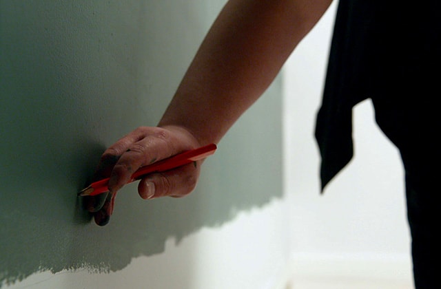 Person freehanding a wavy line on a wall