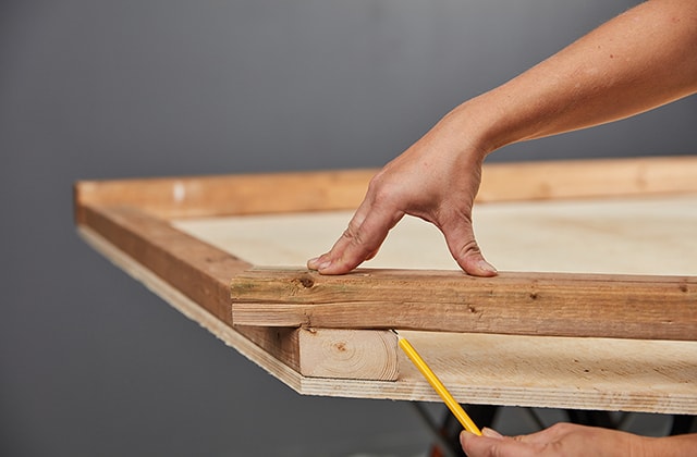 Person placing a piece of wood over another piece to trace an angle