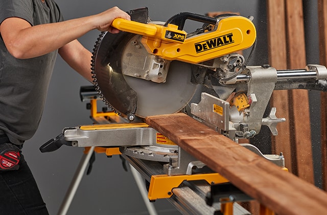 Personne coupant des planches de bois traité