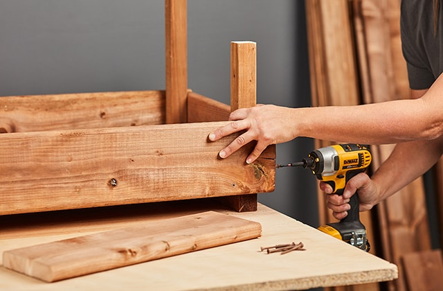 Personne ajoutant une rangée de planches autour d’une boîte à fleurs