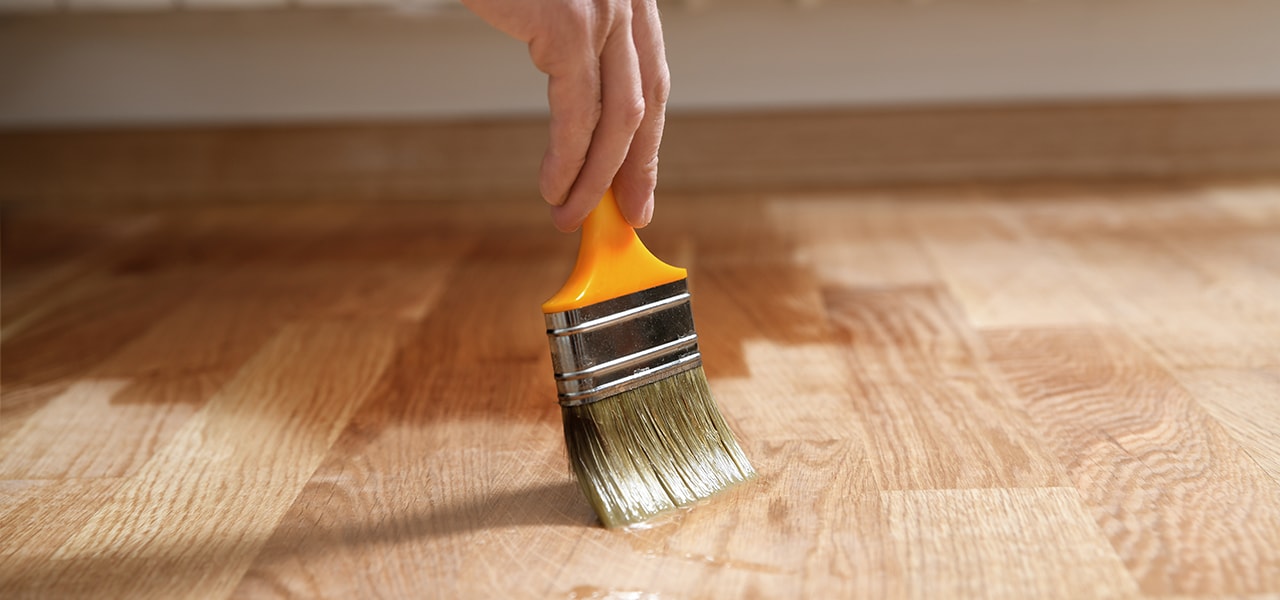 Person applying varnish to a hardwood floor