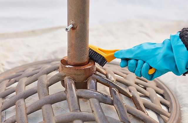 Person brushing a rusted umbrella support