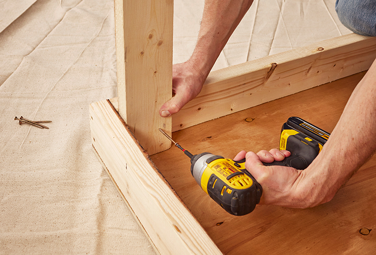 Person securing a wooden plank with screws