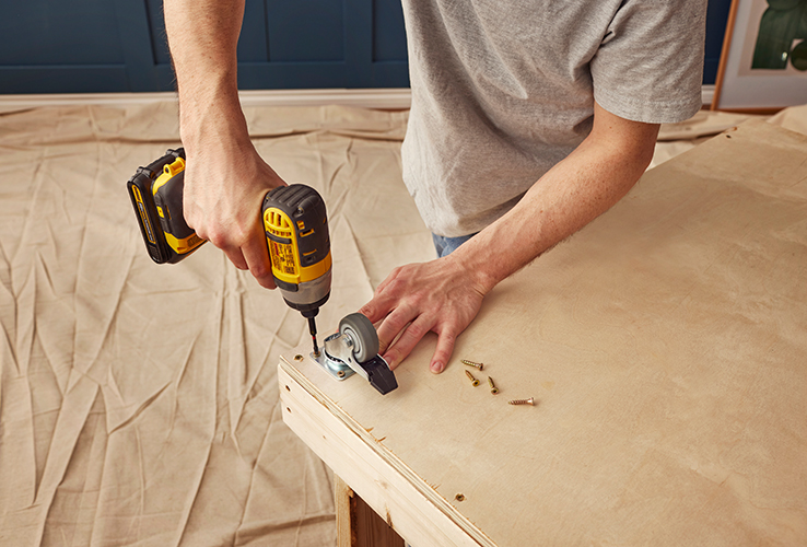 Person adding caster wheels to a wooden structure