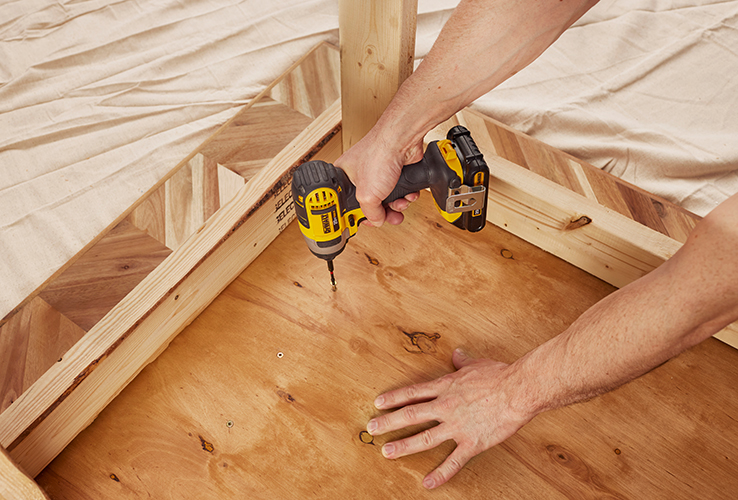 Person securing a countertop with screws