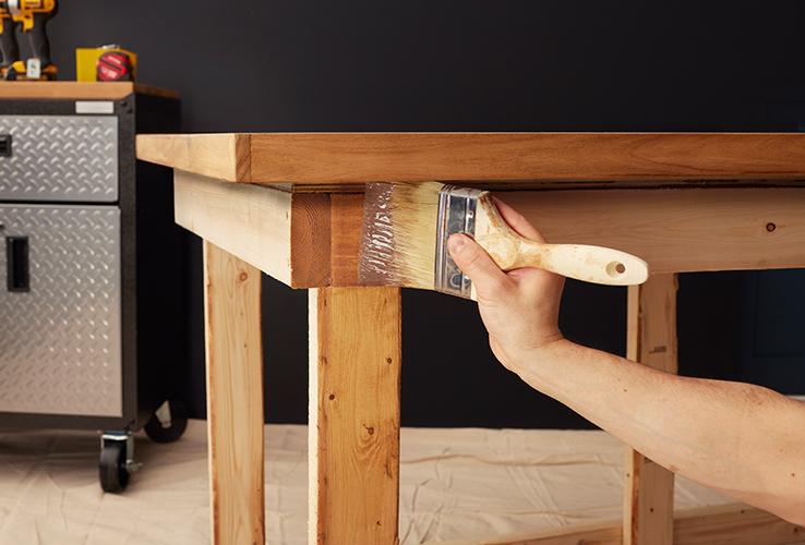 Person applying wood stain with a brush