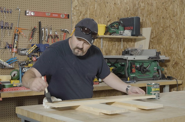 Person apply varnish to a wood plank