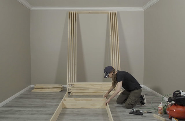 Personne qui construit une structure en bois sur la plancher