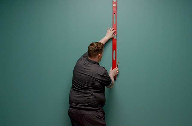 Person tracing a vertical line on a wall