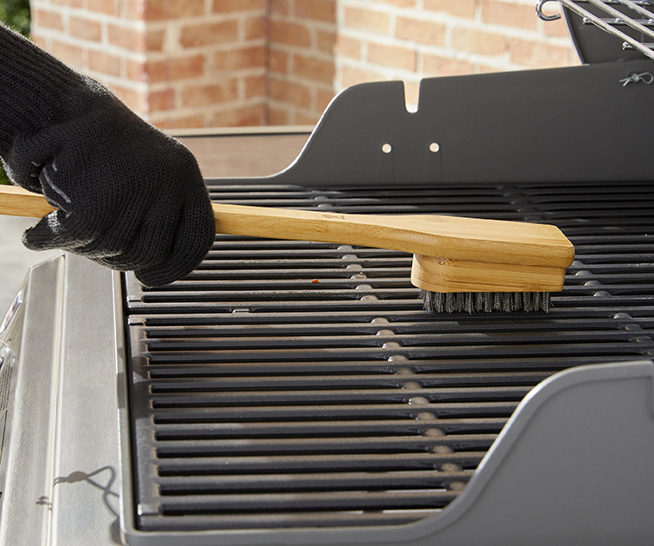 Personne nettoyant un barbecue à l’aide d’une brosse